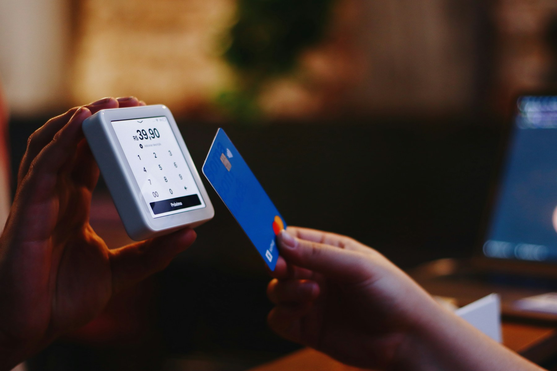 Customer presenting a payment card to a compact contactless terminal in a real retail transaction.