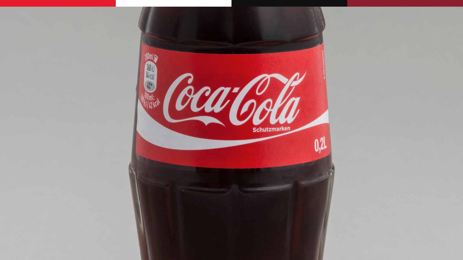 Coca-Cola bottle label close crop showing script and red package visibility.