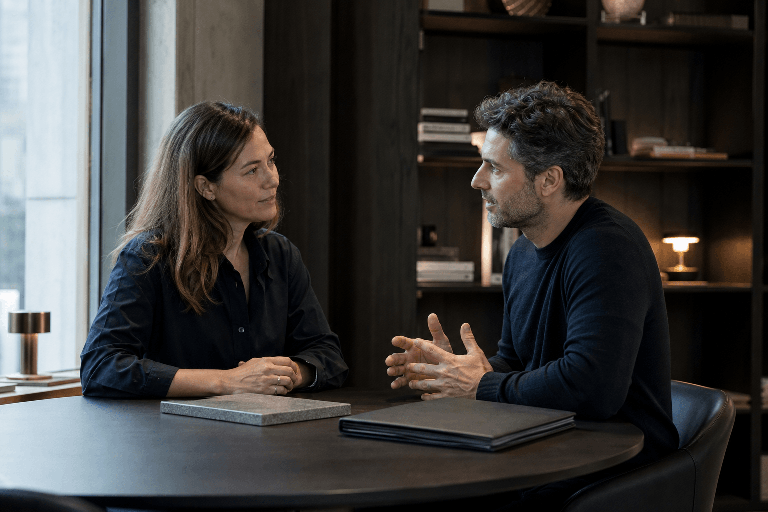 Two professionals having a focused opportunity conversation with a physical work sample between them.