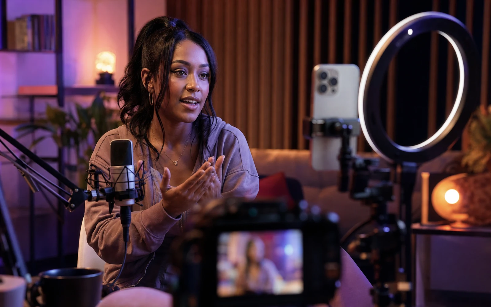 A creator records vertical video in a professional studio with a phone rig, camera, and microphone.