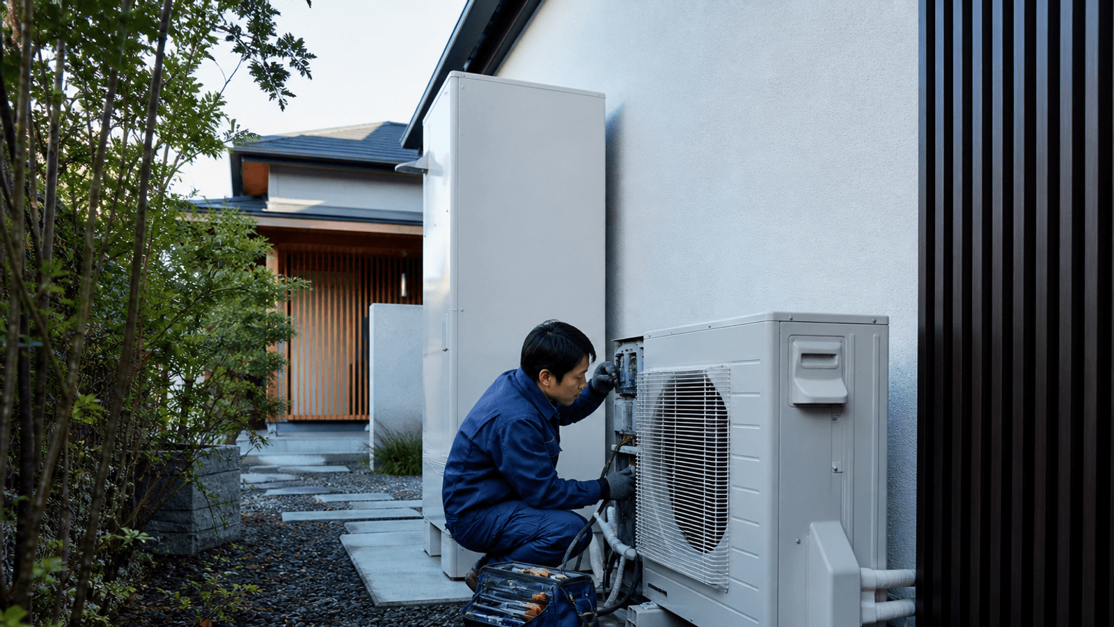 Technician inspecting a modern heat-pump and climate system without visible branding.
