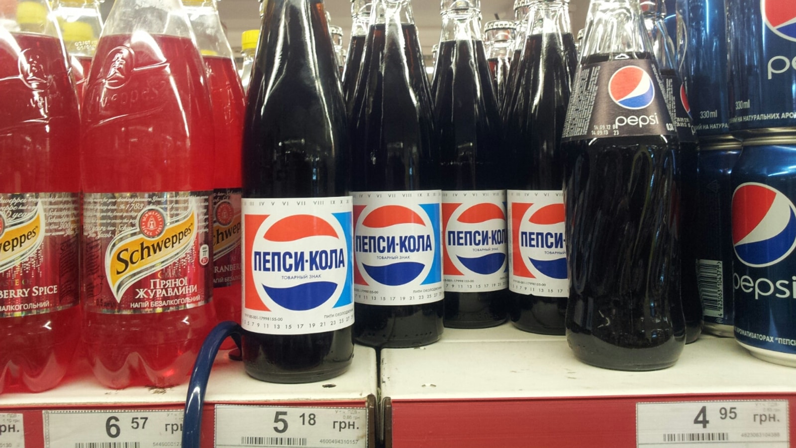 Classic Pepsi bottles in a supermarket cooler row.