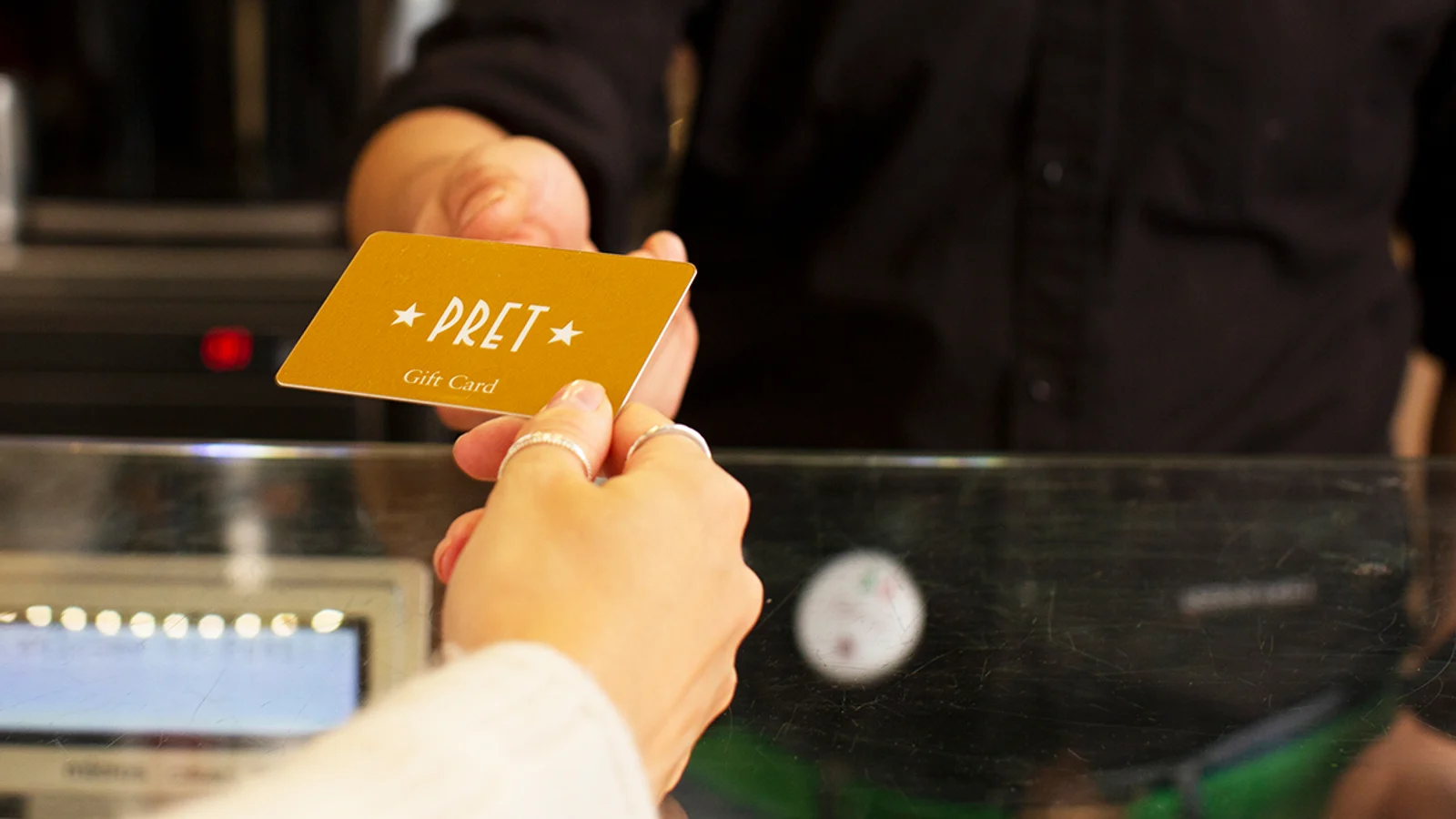 Pret gift card being handed over during an in-shop transaction.