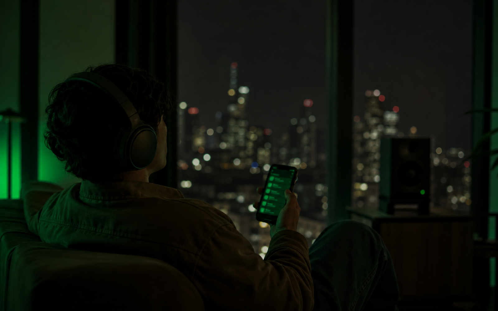 Premium Spotify-style night listening scene with headphones, phone glow, and green-black ambience without readable text.