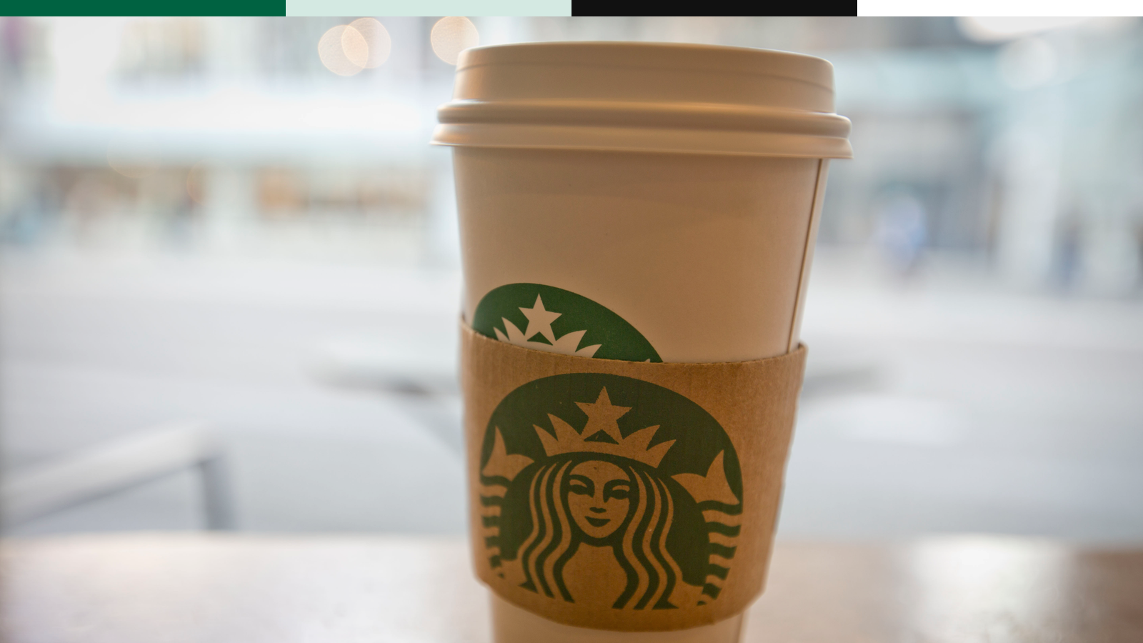 Starbucks hot cup on a table with the green siren visible.
