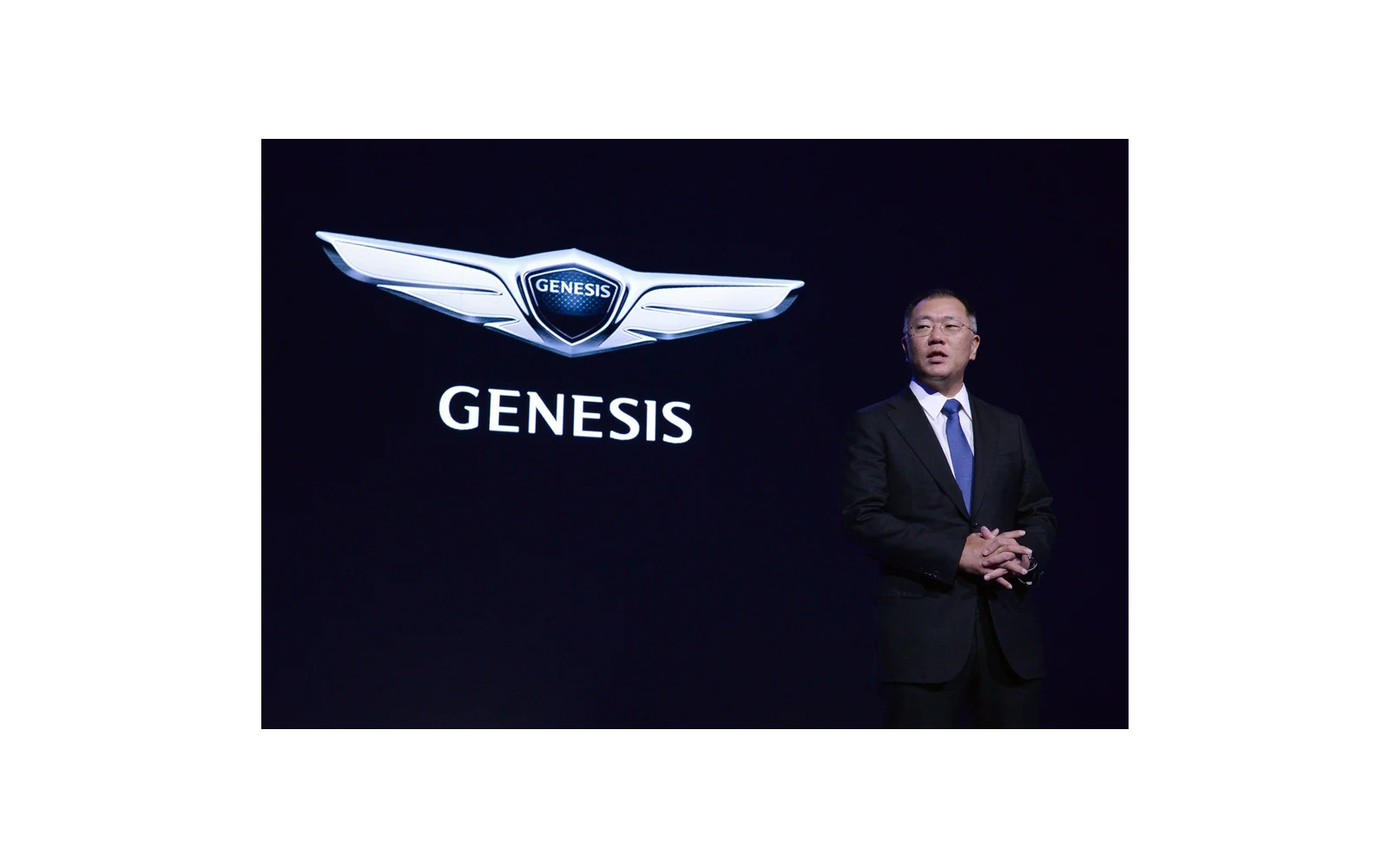Genesis launch speaker beside the Genesis identity