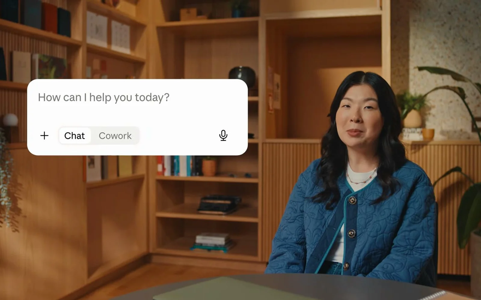 Official Claude product campaign photograph showing a person beside the Claude Chat and Cowork prompt interface.