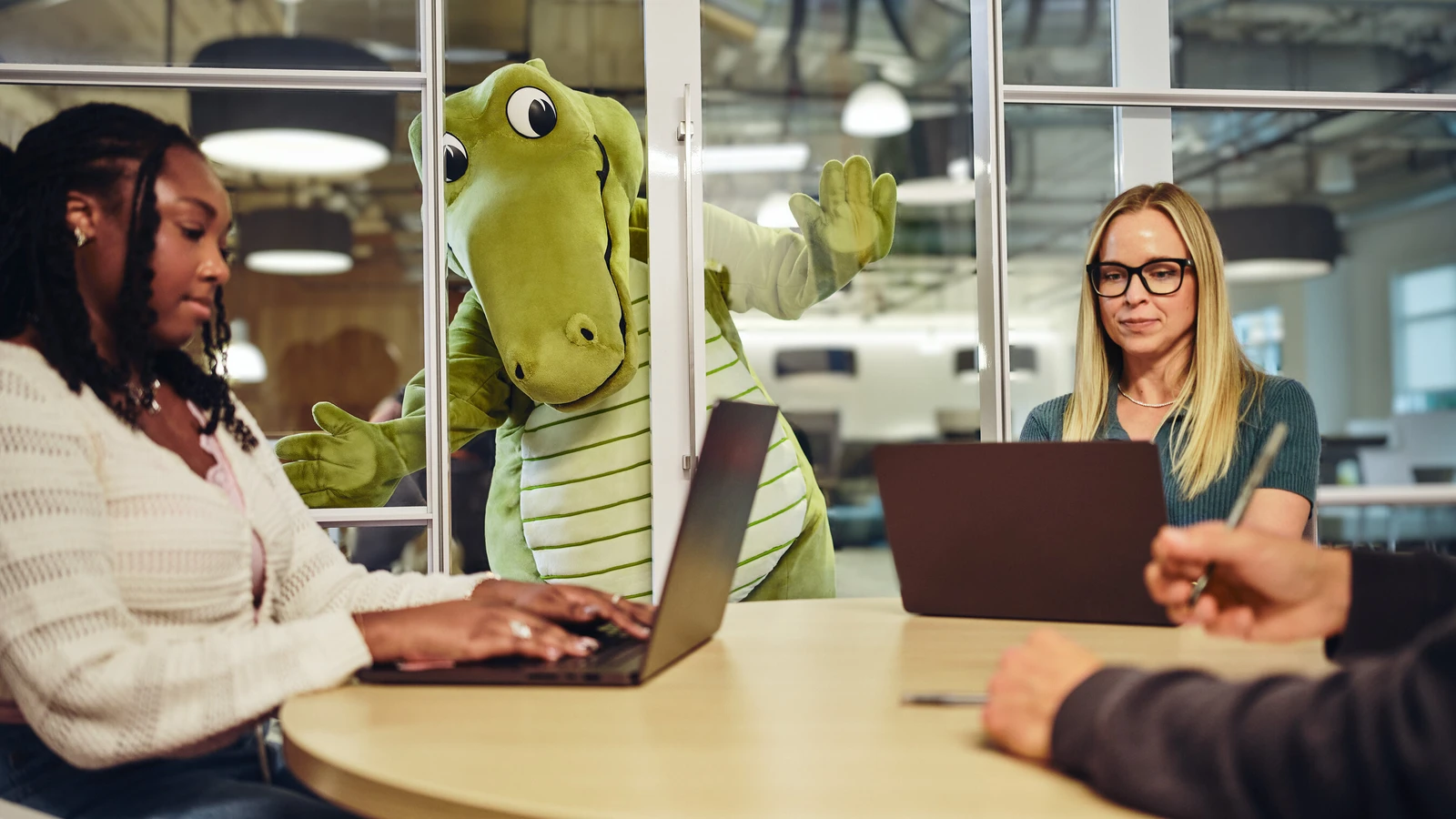 Crocs mascot Niles joins employees around a meeting table at Crocs headquarters.