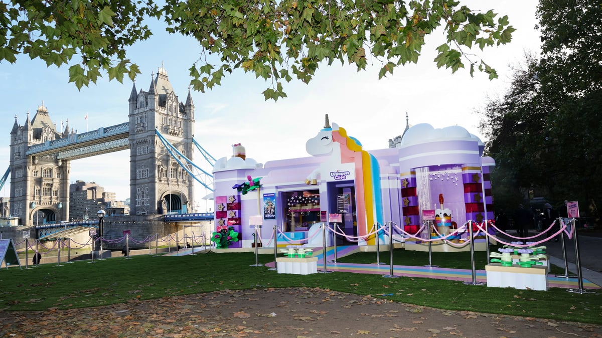 The purple LEGO Friends Unicorn Café pop-up at Potters Fields Park, with Tower Bridge behind it.