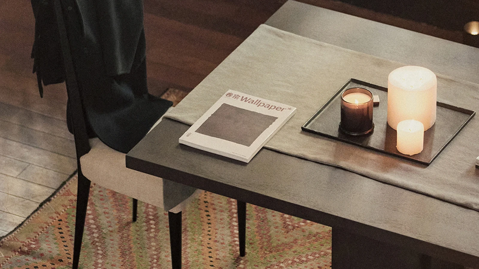 Dark wood table, chair and quiet objects inside the Massimo Dutti pop-up.