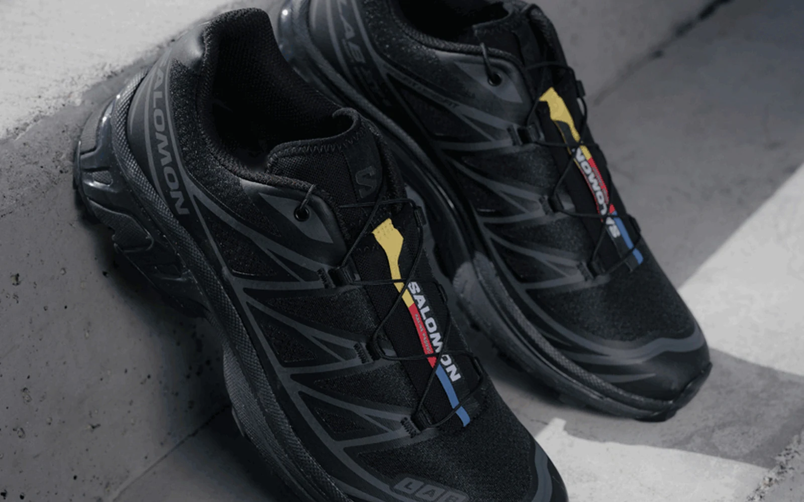 Black Salomon XT-6 shoes photographed on dark concrete steps.