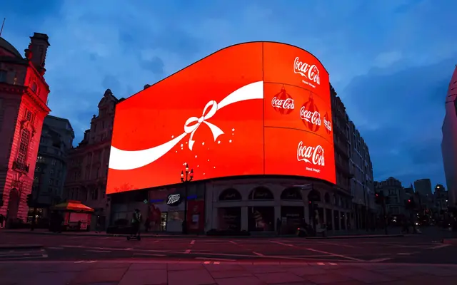 Coca-Cola red Piccadilly Circus billboard with ribbon, script marks, and Real Magic public advertising memory.
