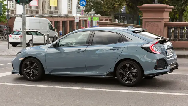 Honda Civic side profile on a city street with the Honda wheel mark visible.